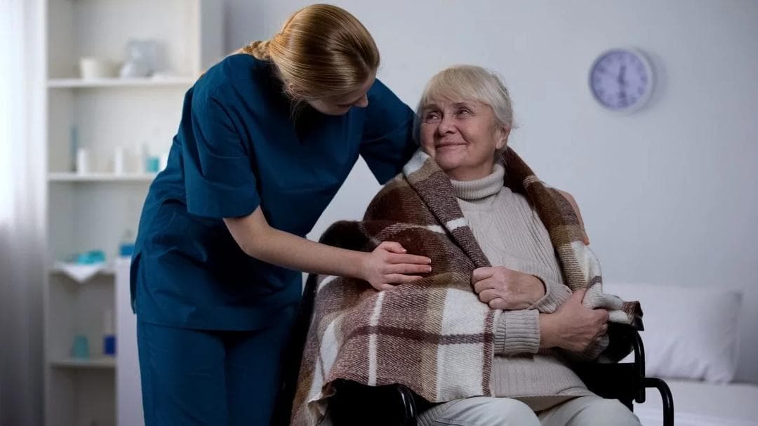 Female nurse tending to male patient in hospital bed